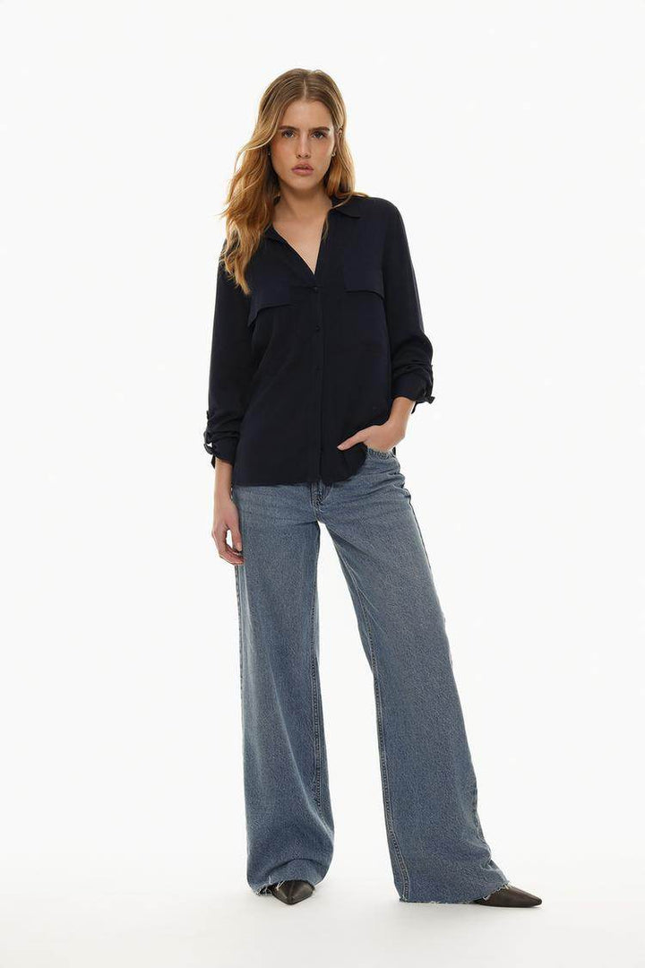 Full body front view of woman wearing navy shirt with pockets

