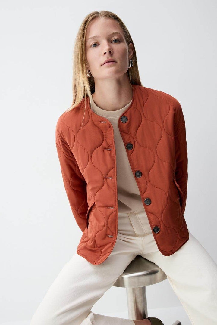 Close-up front view of the women's orange quilted jacket

