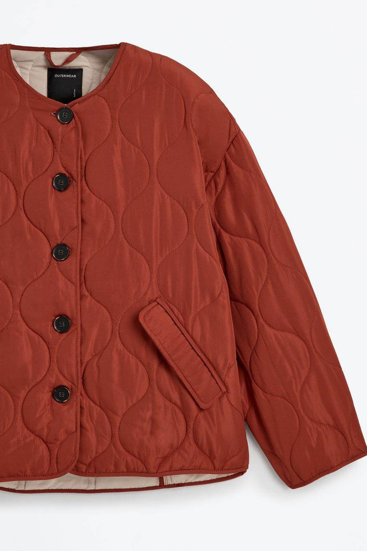 Close-up product image of the orange quilted jacket's fabric and stitching

