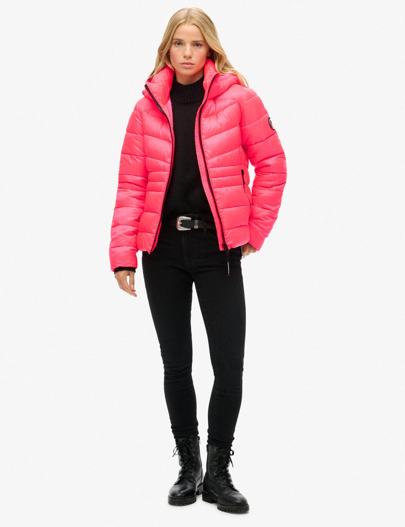 Full body view of a woman wearing a pink hooded puffer jacket

