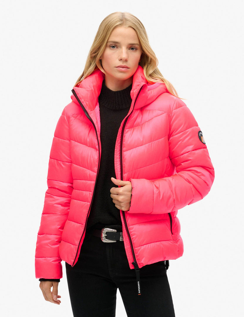 Full body view of a woman wearing a pink hooded puffer jacket

