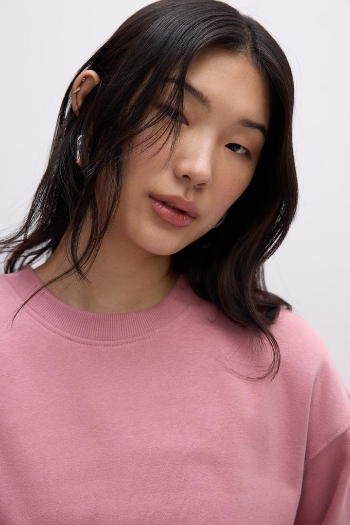 Zoomed front view of the collar of a pink women's sweatshirt
