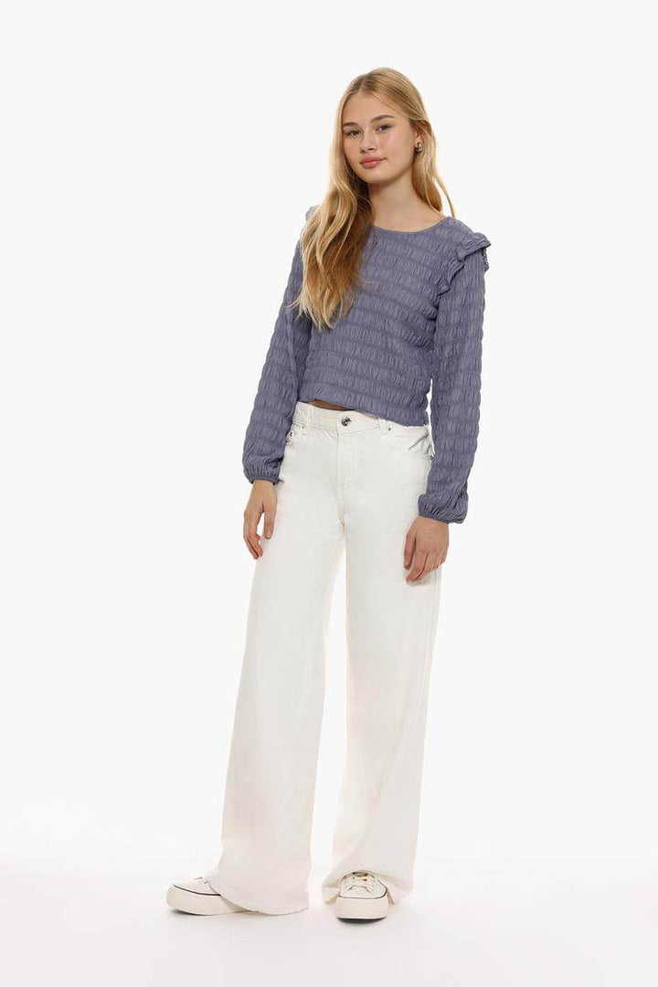 Full body front view of woman wearing purple ruffle blouse

