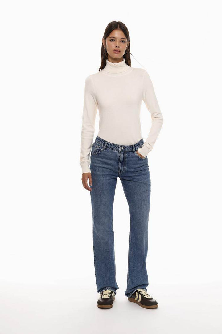 Full body front view of woman wearing white turtleneck sweater

