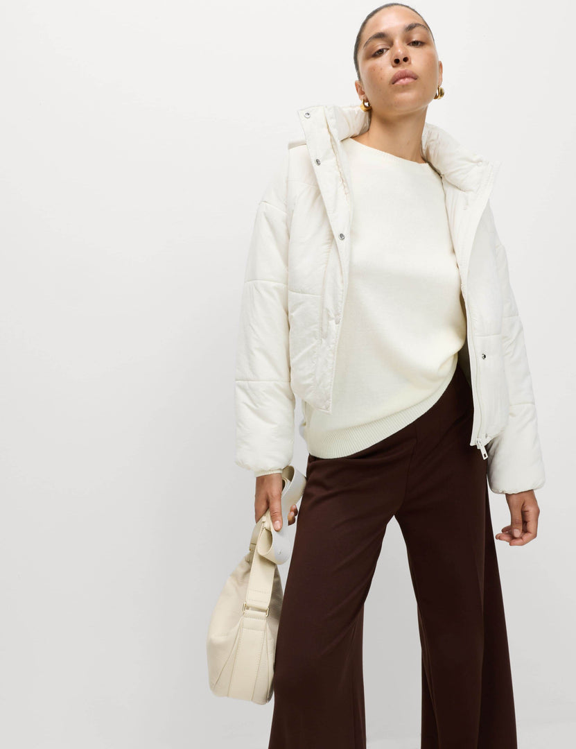 Full body front view of a woman wearing a white hooded puffer jacket

