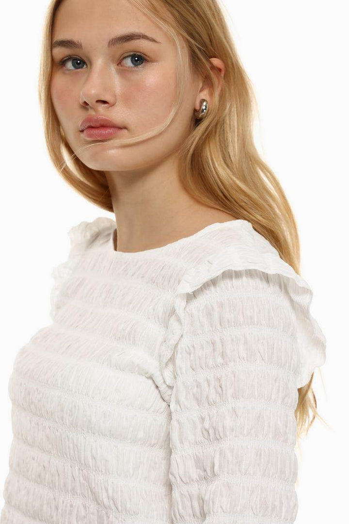 Close-up front view of white ruffle blouse details

