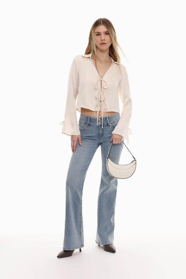 Full body front view of woman wearing white satin shirt with ties

