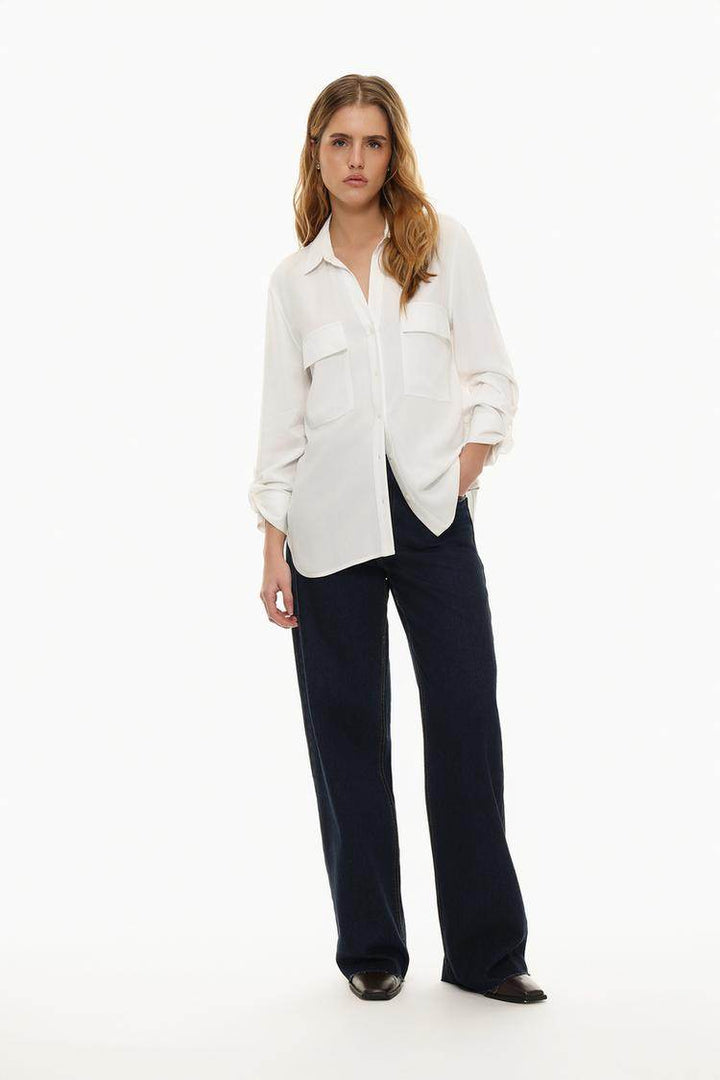 Full body front view of woman wearing white shirt with pockets

